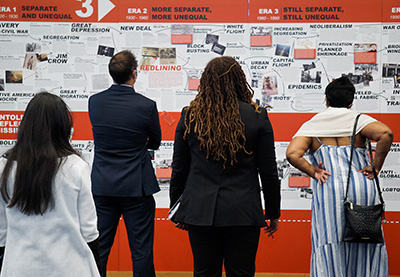 patrons stand and view a wall exhibit