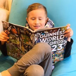 Young child sitting in chair, holding a large book