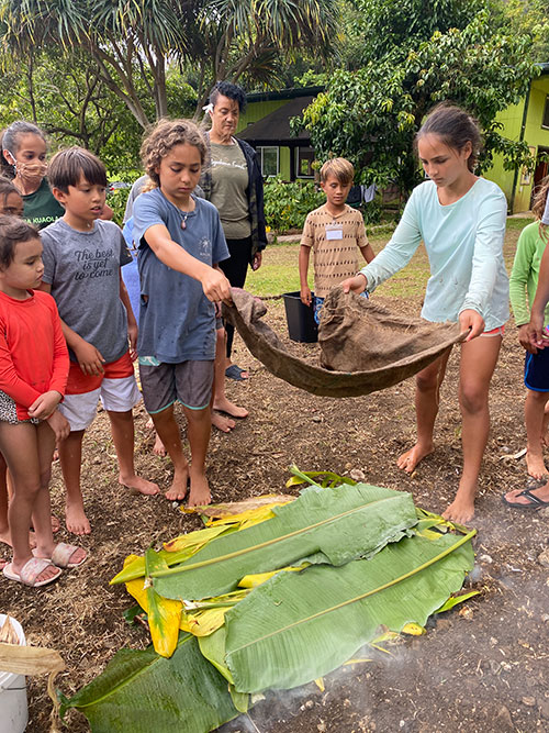 a group of children laying cloth over leaves