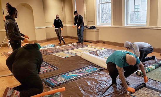 A group of people working on a rug in a room