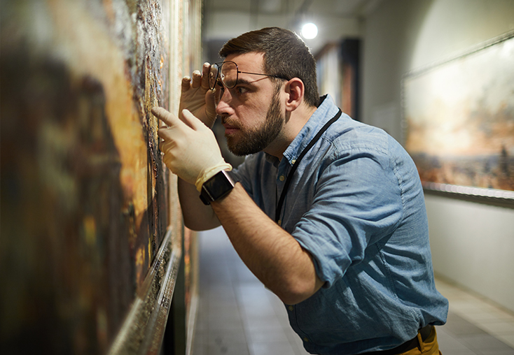 Museum conservator examines a painting