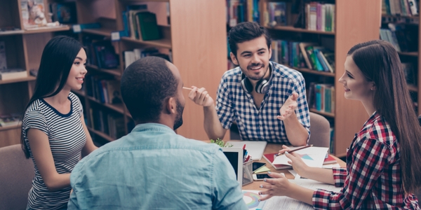 Four adult students sitting at table in library