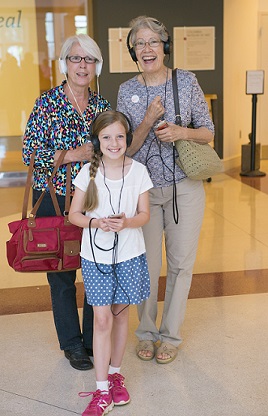 Mother, grandmother, and daughter listen to audio tour