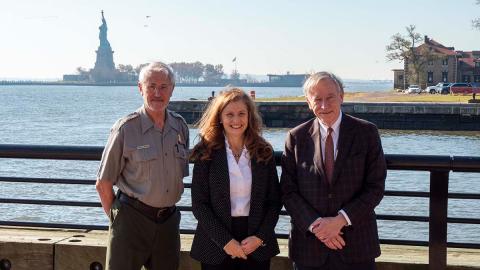 Three people standing for photo, Statue of Liberty in the background