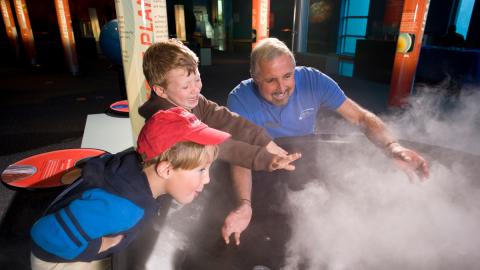 Museum volunteer and two young visitors explore the mysteries clouds.