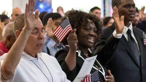 People holding flags during a citizenship swearing-in ceremony.