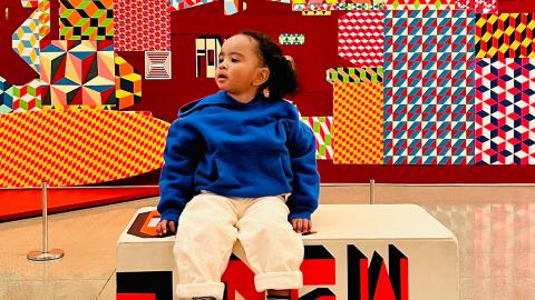 Little boy sitting in front of art display